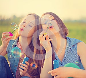 Beauty girls blowing soap bubbles in spring park
