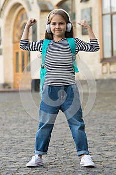 Beauty gives power. Small kid flex arms outdoors. Girl power. Little child listen to music in headphones. Music is power