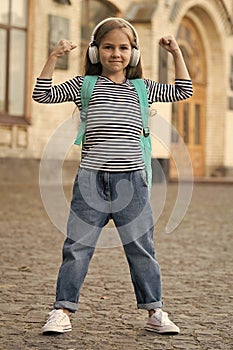 Beauty gives power. Small kid flex arms outdoors. Girl power. Little child listen to music in headphones. Music is power