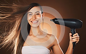 Beauty, hair and hairdryer with a model woman in studio on a brown background for blowdrying or treatment. Portrait