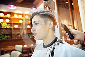 Beauty, hairstyle, treatment, hair care concept, young woman and hairdresser cutting hair at hairdressing salon. Hairdresser cuts