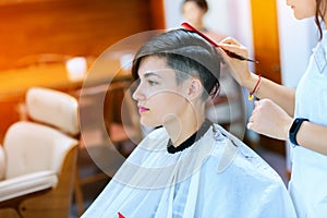 Beauty, hairstyle, treatment, hair care concept, young woman and hairdresser cutting hair at hairdressing salon. Hairdresser cutts