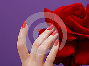 Beauty hands with red fashion manicure and bright flower . Beautiful manicured red polish on nails . Fasionable cosmetics and