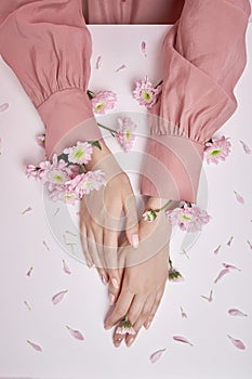 Beauty hands woman with pink flowers are on the table. Natural cosmetic for hand skin care. Perfect nails