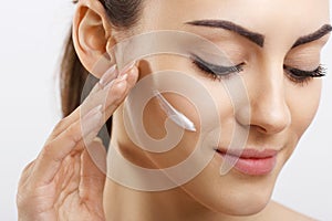 Beauty Happy young woman applying cream to her face. Skincare and cosmetics concept.Cosmetics. Woman face skin care.Spa