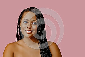 beauty headshot of smiling young adult black woman braid hair on pink background looking away at copy space