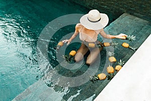 Beautiful Woman Relaxing In Swimming Pool With Pineapples. Healthy Lifestyle, Nutrition, Diet. Summer Vacation