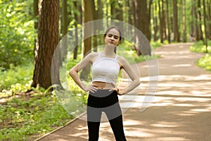 Beauty, health, fitness. Girl warming up in the park before jogging, doing exercises in nature