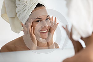 After beauty home procedure woman looking at skin feels satisfied