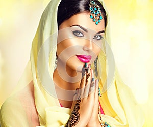 Beauty Indian girl with mehndi tattoos hold palms together