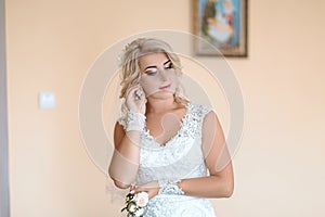 Beauty and jewelery concept - woman wearing shiny diamond earrings, the bride wears earrings, in a white wedding dress and gloves