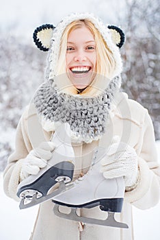 Beauty Joyful Girl having fun in winter park. Beautiful smiling young woman in warm clothing with ice skates. Winter