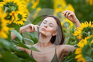 Beauty joyful girl with sunflower enjoying nature  on the field of sunflowers at sunset