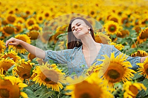 Beauty joyful girl with sunflower enjoying nature and laughing on the field of sunflowers at sunset
