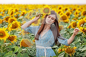 Beauty joyful girl with sunflower enjoying nature and laughing on the field of sunflowers at sunset. Copy space