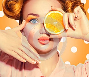 Beauty joyful teenage girl takes juicy oranges. Teen model girl with freckles, funny red hairstyle, yellow makeup and nails