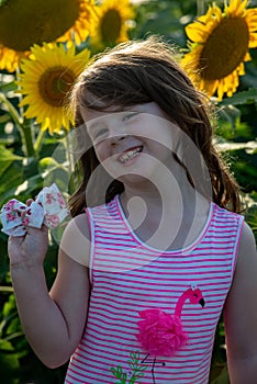 Beauty joyful young girl with sunflower enjoying nature and laughing on summer sunflower field. Sunflare, sunbeams, glow