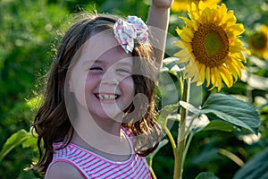 Beauty joyful young girl with sunflower enjoying nature and laughing on summer sunflower field. Sunflare, sunbeams, glow