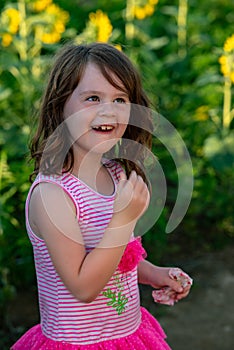 Beauty joyful young girl with sunflower enjoying nature and laughing on summer sunflower field. Sunflare, sunbeams, glow