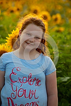 Beauty joyful young girl with sunflower enjoying nature and laughing on summer sunflower field. Sunflare, sunbeams, glow