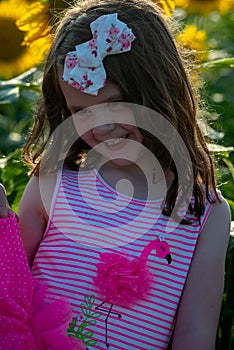 Beauty joyful young girl with sunflower enjoying nature and laughing on summer sunflower field. Sunflare, sunbeams, glow