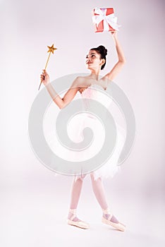 The beauty lady is wearing pink ballet suit,dancing and raise wand star and gift box up in the air