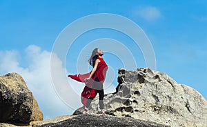 The beauty lady wearing red suit and satin ballet shoes, steping and posing ballet pattern on big rock