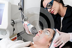 Beauty laser technician performing skin resurfacing procedure in a medical spa and beauty clinic. Caucasian female patient photo