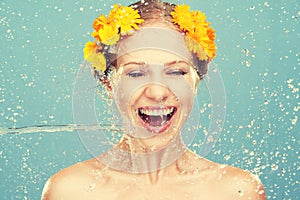 Beauty laughing girl with splashes of water and yellow flowers