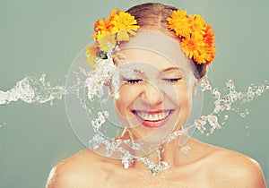 Beauty laughing girl with splashes of water and yellow flowers