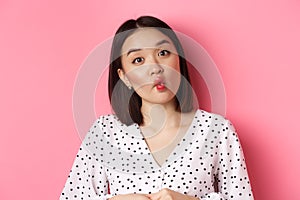 Beauty and lifestyle concept. Close-up of funny and cute asian woman pucker lips, showing fish mouth and standing