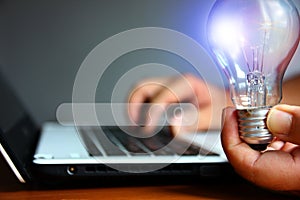 Beauty light bulb in left hand while light hand using laptop with searching channell , idea working concept photo