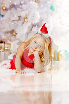 Beauty little Santa girl near the Christmas tree. Happy girl ce