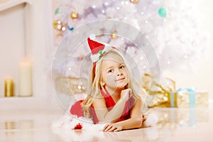 Beauty little Santa girl near the Christmas tree. Happy girl wi
