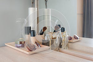 Beauty and make-up concept: table mirror, flowers, perfume, jewelry and makeup brushes on wooden table