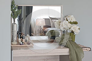 Beauty and make-up concept: table mirror, flowers, perfume, jewelry and makeup brushes on wooden table