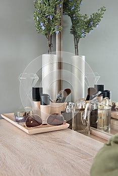 Beauty and make-up concept: table mirror, flowers, perfume, jewelry and makeup brushes on wooden table