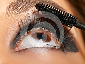 Beauty, makeup and eye of woman with mascara brush on lashes with black eye shadow at fashion show. Art, fashion and eye