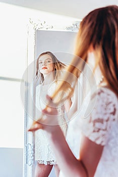 Beauty makeup morning rutine love yourself concept. Young teenage girl looking at reflection in mirror. Young positive woman