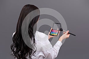 Beauty makeup. Palette of cosmetic eye shadow in the hands of a woman. Woman turned her back to the camera