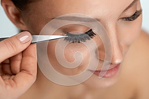 Beauty Makeup. Woman Applying Black False Eyelashes With Tweezer