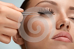 Beauty Makeup. Woman Applying Black False Eyelashes With Tweezer