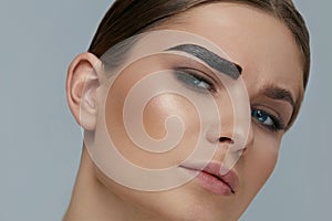 Beauty makeup. Woman coloring eyebrow with brow gel tint