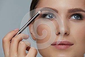 Beauty makeup. Woman shaping eyebrow with brow pencil closeup