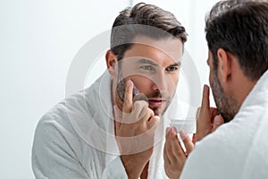 Beauty man applying face cream. Skincare cream, skin anti-aging wrinkle effect. Man applying moisturizer cream on skin