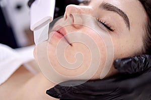 Beauty master makes ultrasonic facial peeling to her client