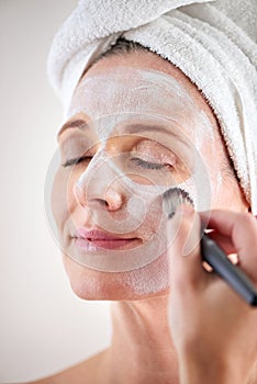 Beauty, mature woman and mask with brush in studio for skincare or anti aging on self care, wellness and fresh skin