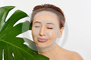 Beauty middle age woman macro face portrait. Spa and anti aging concept and leaf Isolated on white background. Plastic surgery