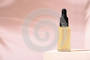 Beauty mineral oil glass bottle with dropper for skin, hair. Product package serum on pink background and white stand