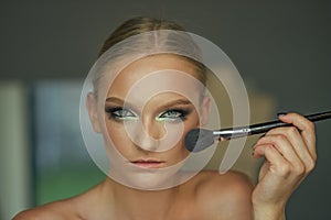 Beauty model apply powder on face, cosmetics. Woman use brush for makeup, visage. Girl skin, skincare, cosmetics. Woman
